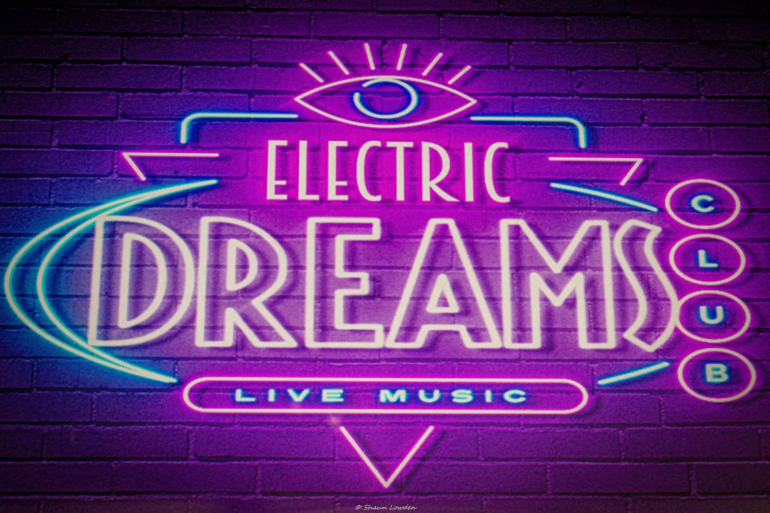 Neon sign reading 'Electric Dreams Live Music' in pink and blue colors.