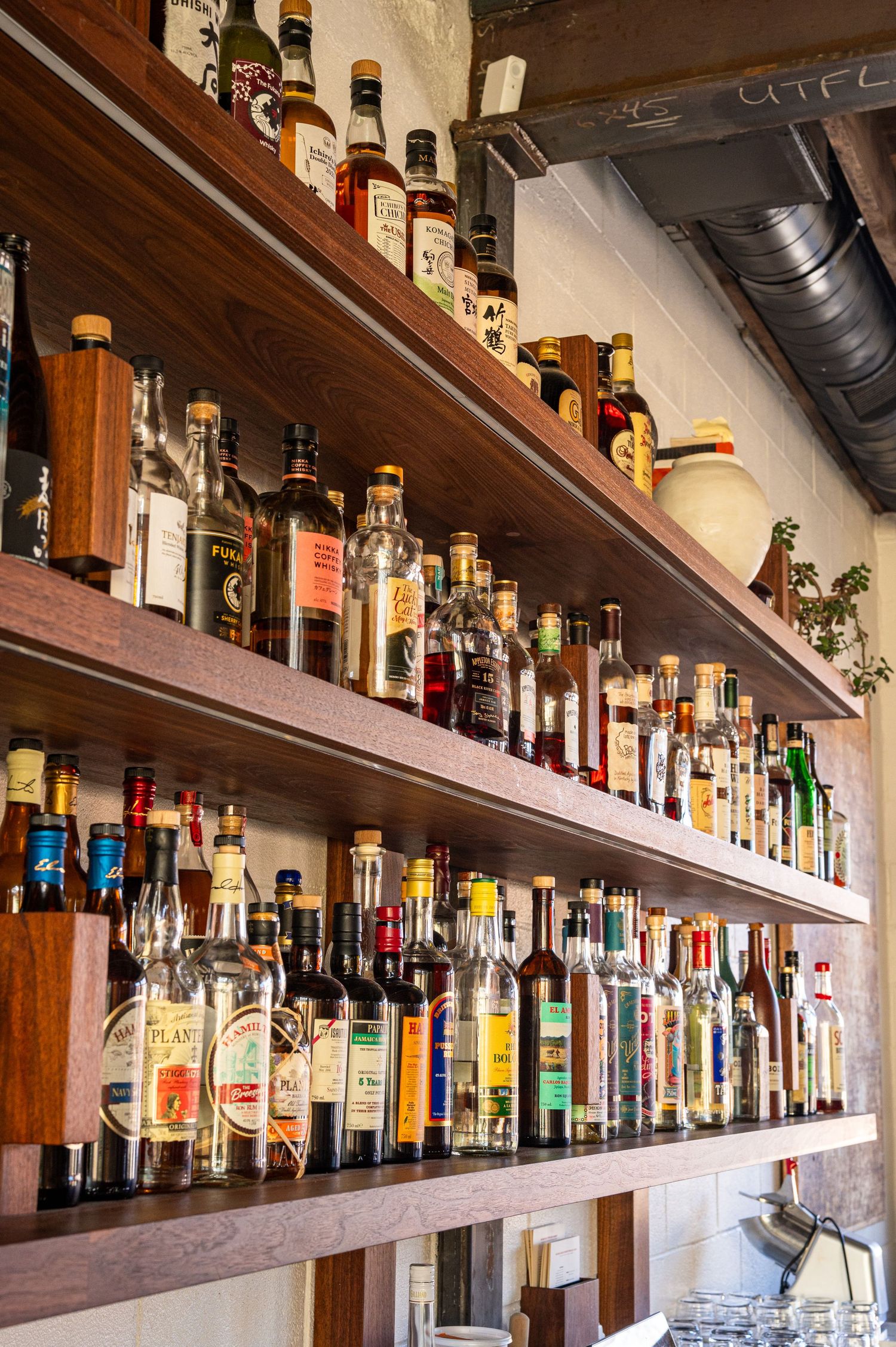 Well-stocked bar shelves displaying rows of diverse liquor bottles including whiskey, rum, and spirits.