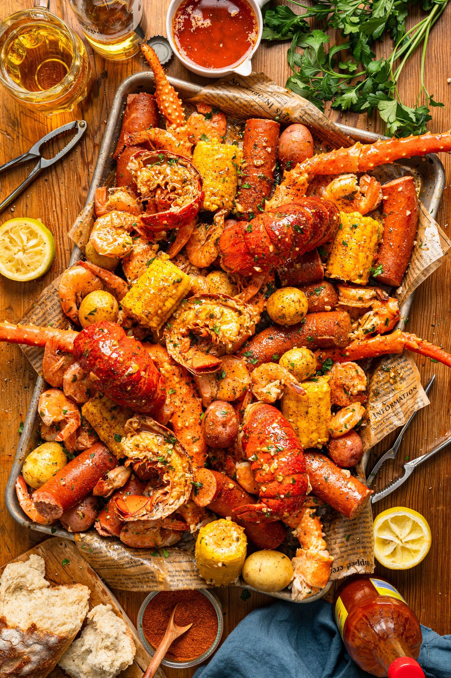 Seafood boil spread with lobster, crab legs, shrimp, corn, sausage, and potatoes on sheet pan.