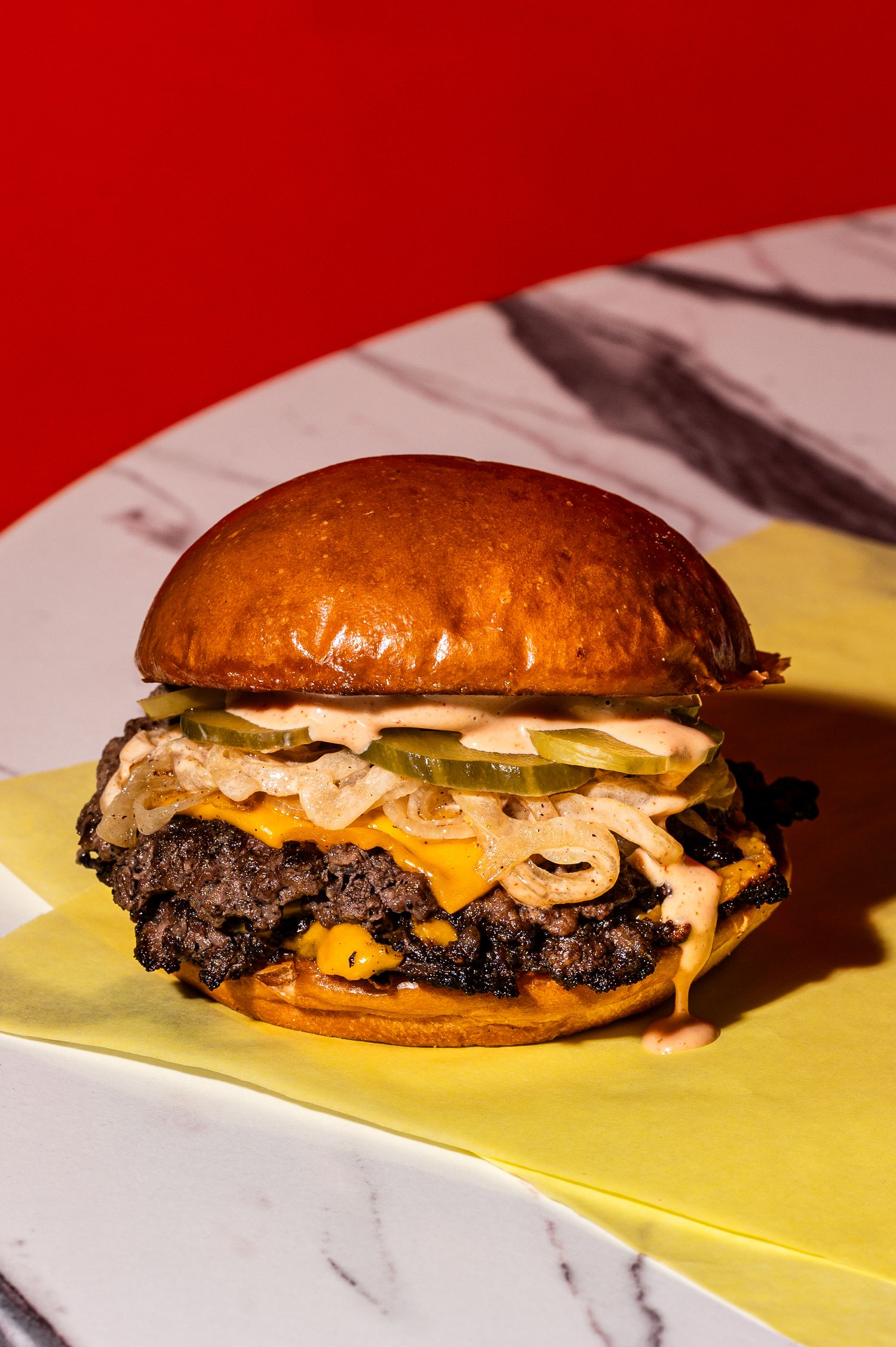 Juicy smash burger with melted cheese, caramelized onions, pickles, and special sauce on a toasted brioche bun.