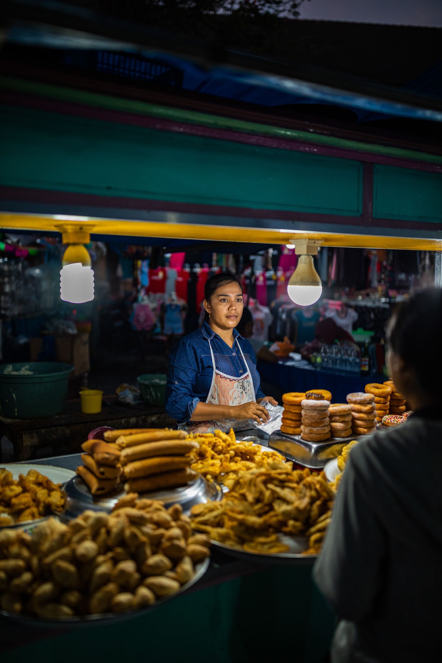 Night market food stall displaying freshly baked breads and pastries under warm lighting.