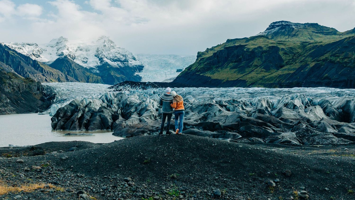 Panoramic view of snow-capped mountains and glaciers in Iceland with dramatic cloudy skies.