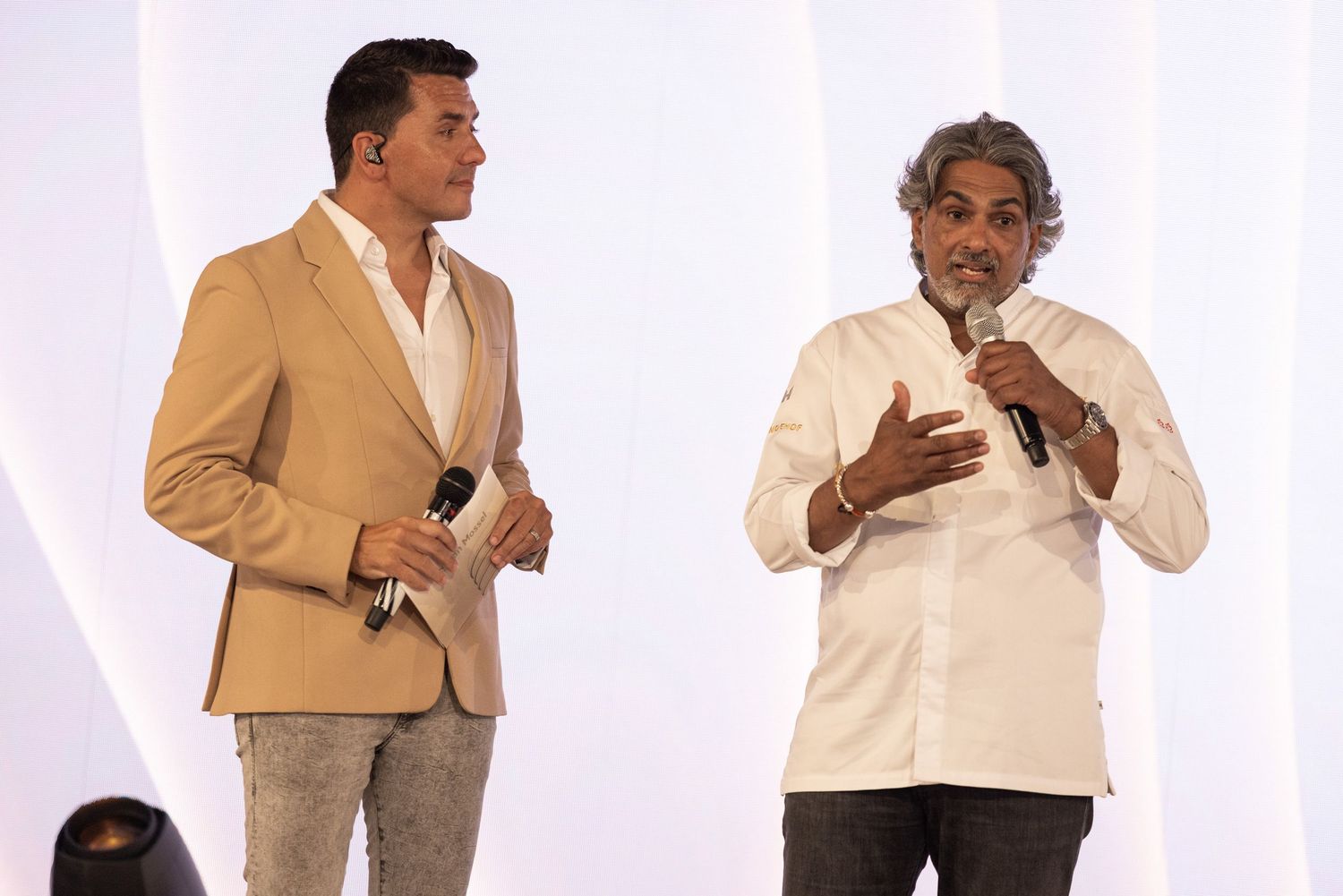 Two people in business attire engage in an animated conversation against a white background.