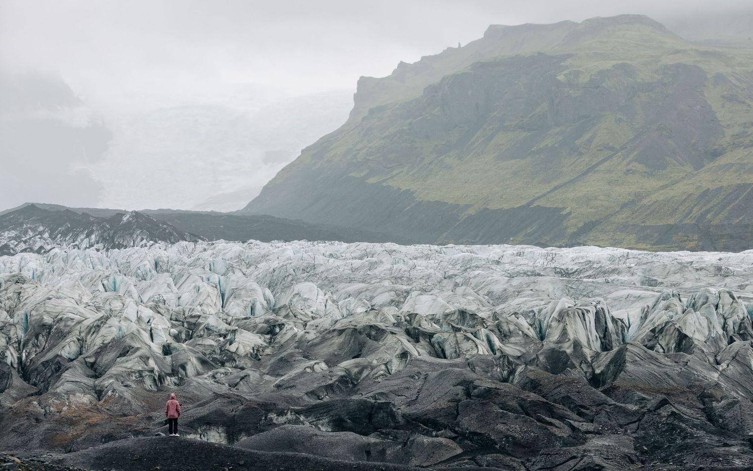 Vast glacier field stretches across rugged Icelandic landscape with misty mountain peaks in the background.