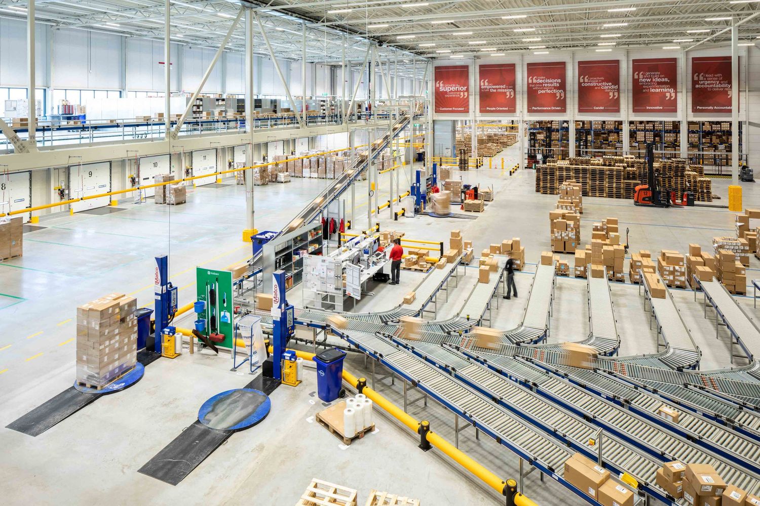 Large industrial warehouse interior with conveyor belts and storage racks.