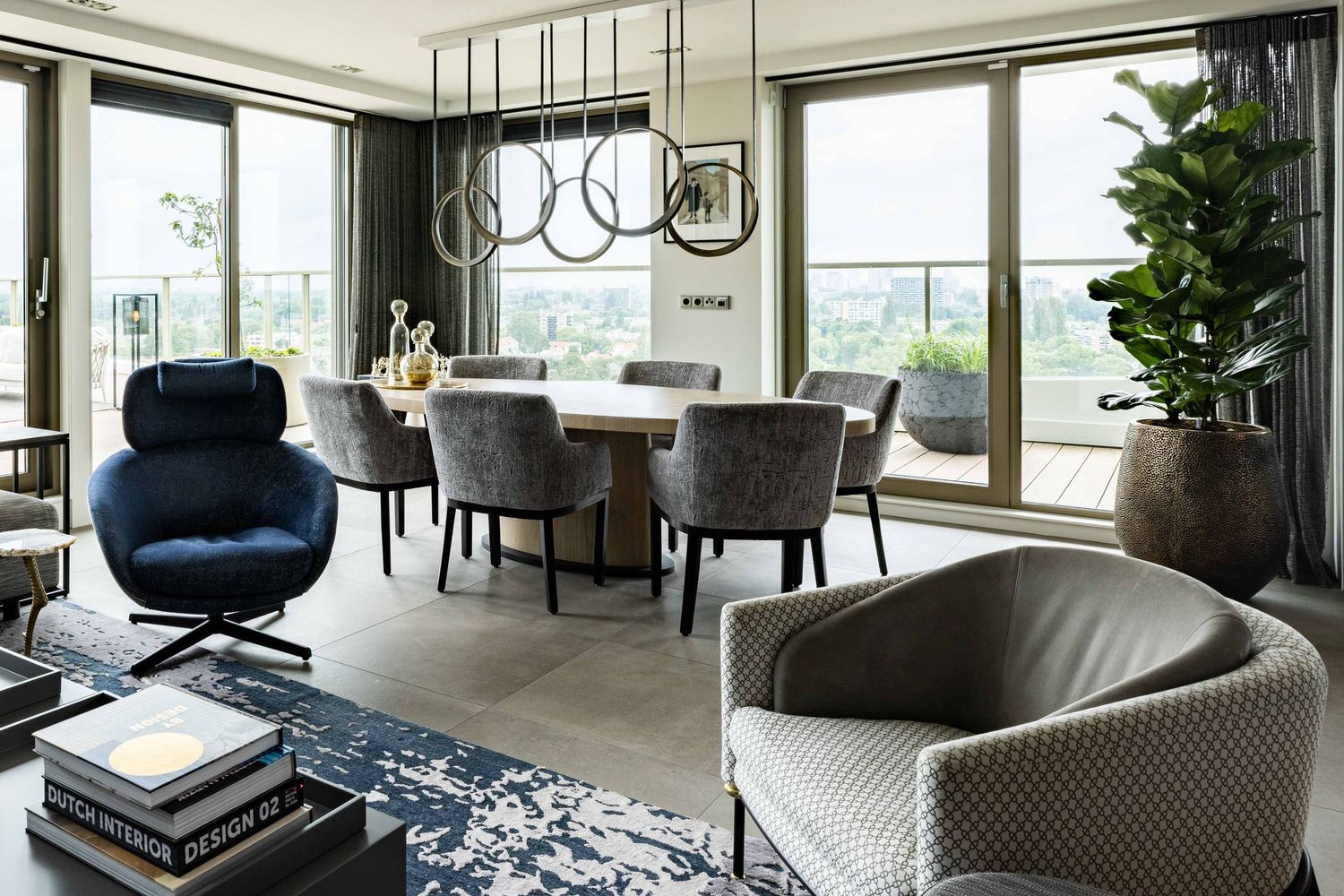 Modern luxury apartment interior with panoramic windows, curved sofa, and contemporary decor in neutral tones.