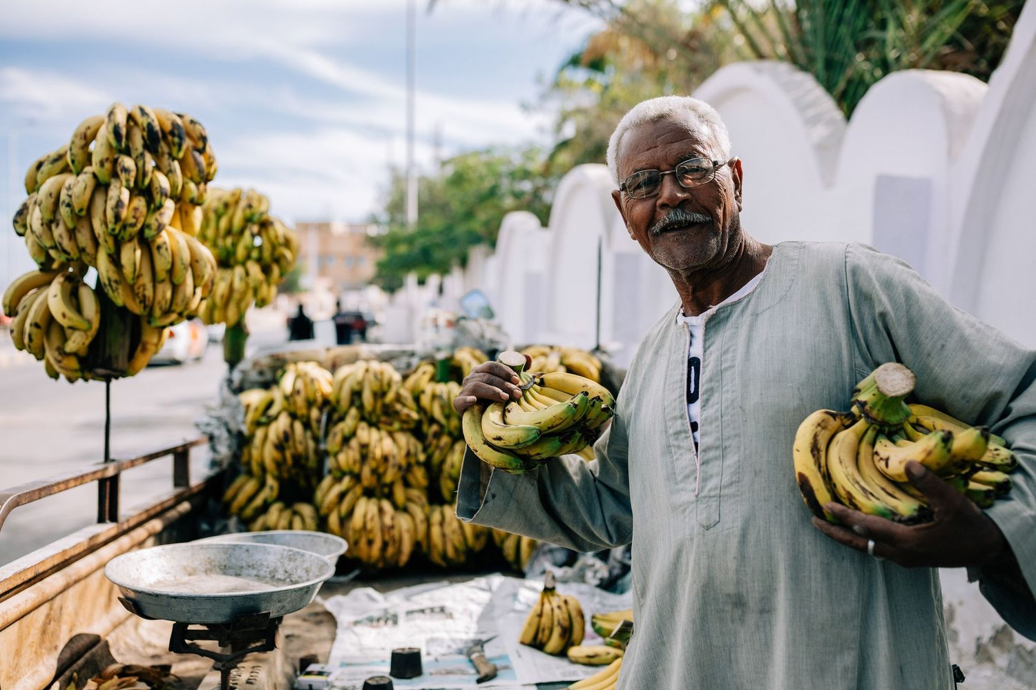 Fresh yellow bananas being displayed at an outdoor market stall.