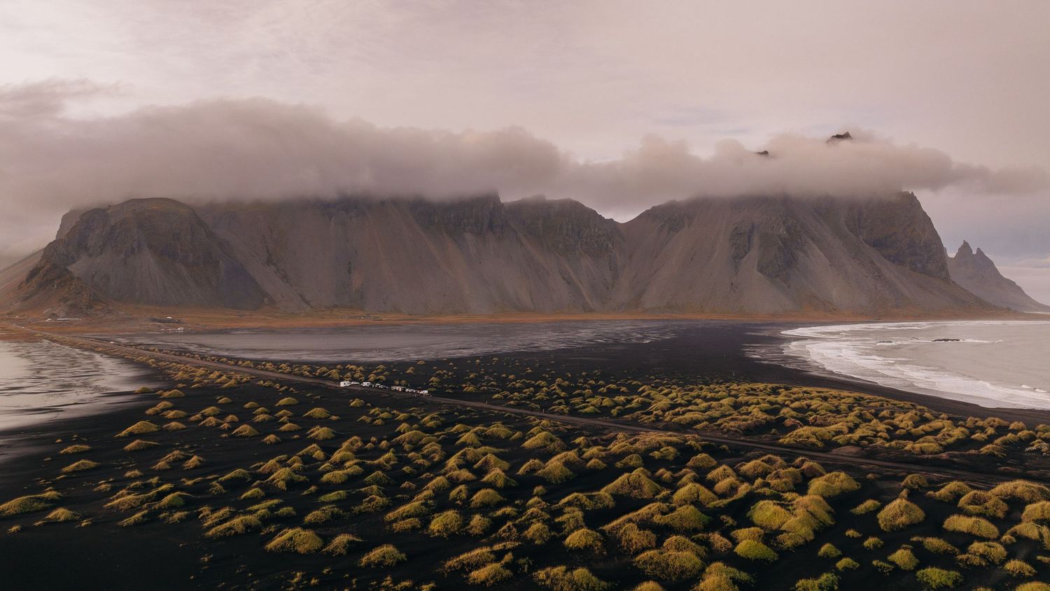 A panoramic view of misty mountains and valleys stretches across the horizon in dramatic lighting conditions.