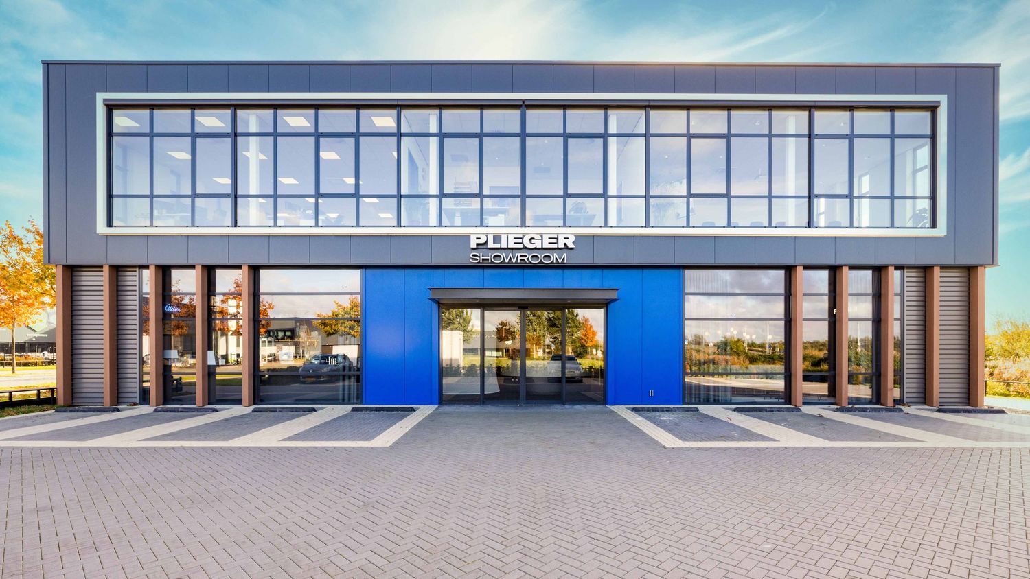 A panoramic view of a modern retail storefront with glass windows and blue accents during daytime.