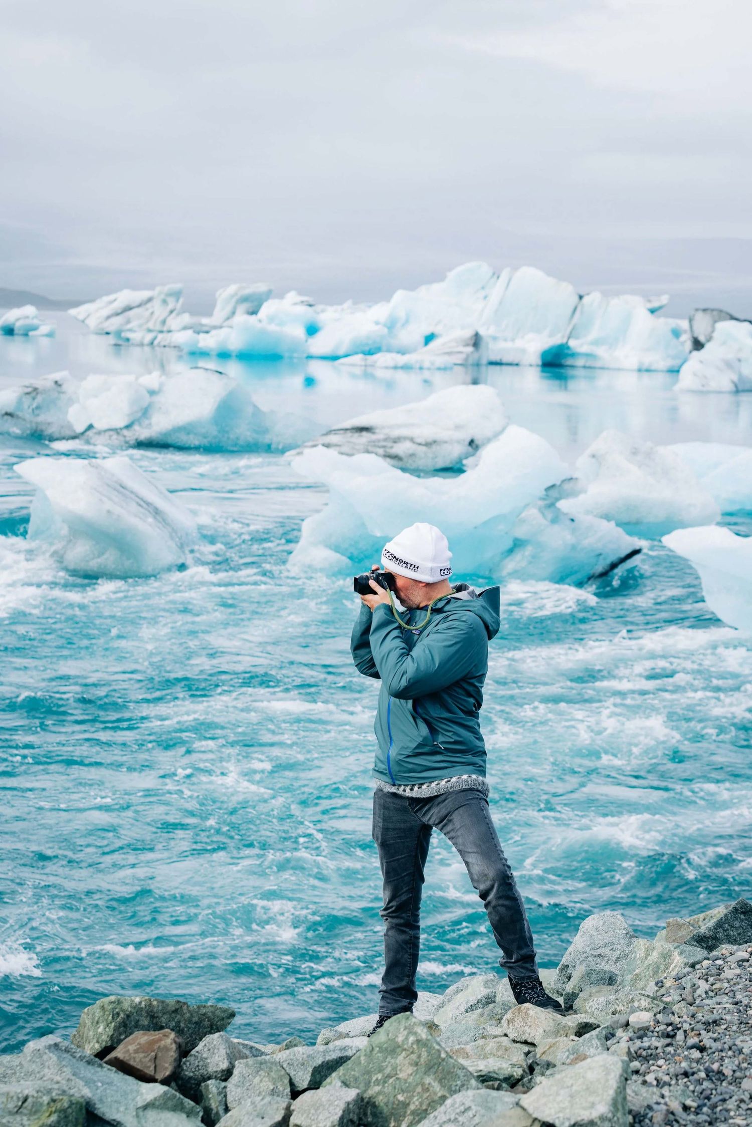 A photographer captures images of blue icebergs floating in glacial waters.