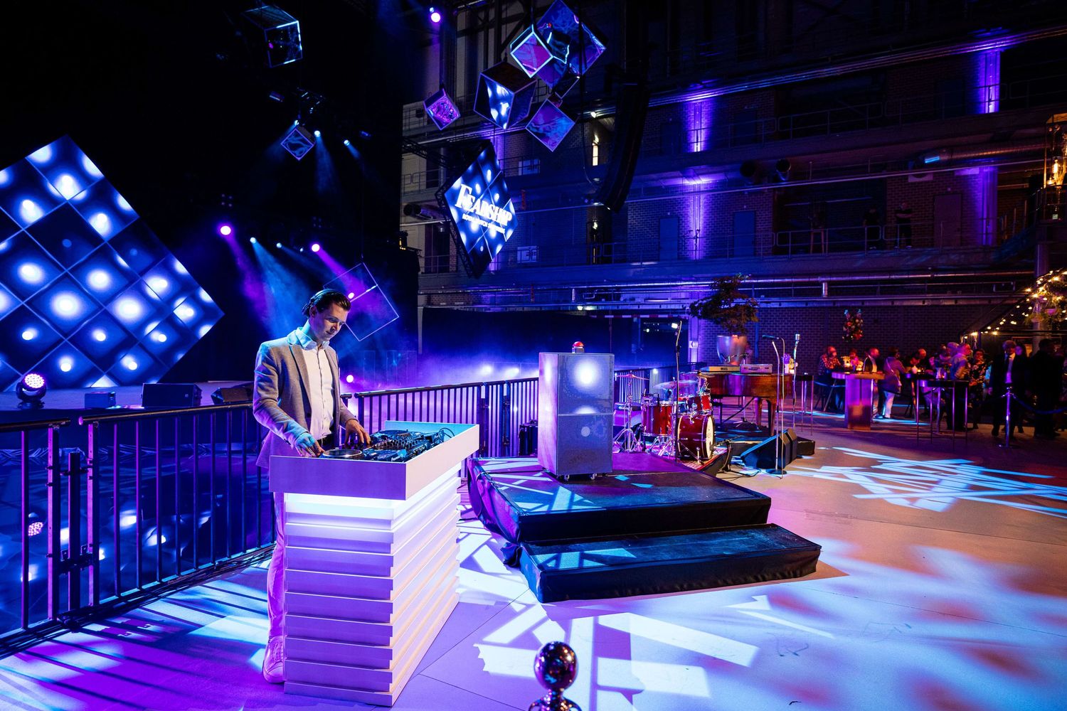 Colorful blue and purple lighting illuminates an indoor skating rink with skaters gliding across the smooth surface.