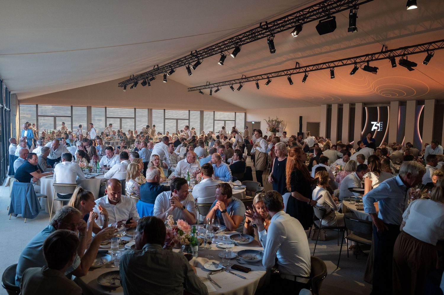 Large crowd of people seated in rows at a business conference or corporate event in a modern venue.