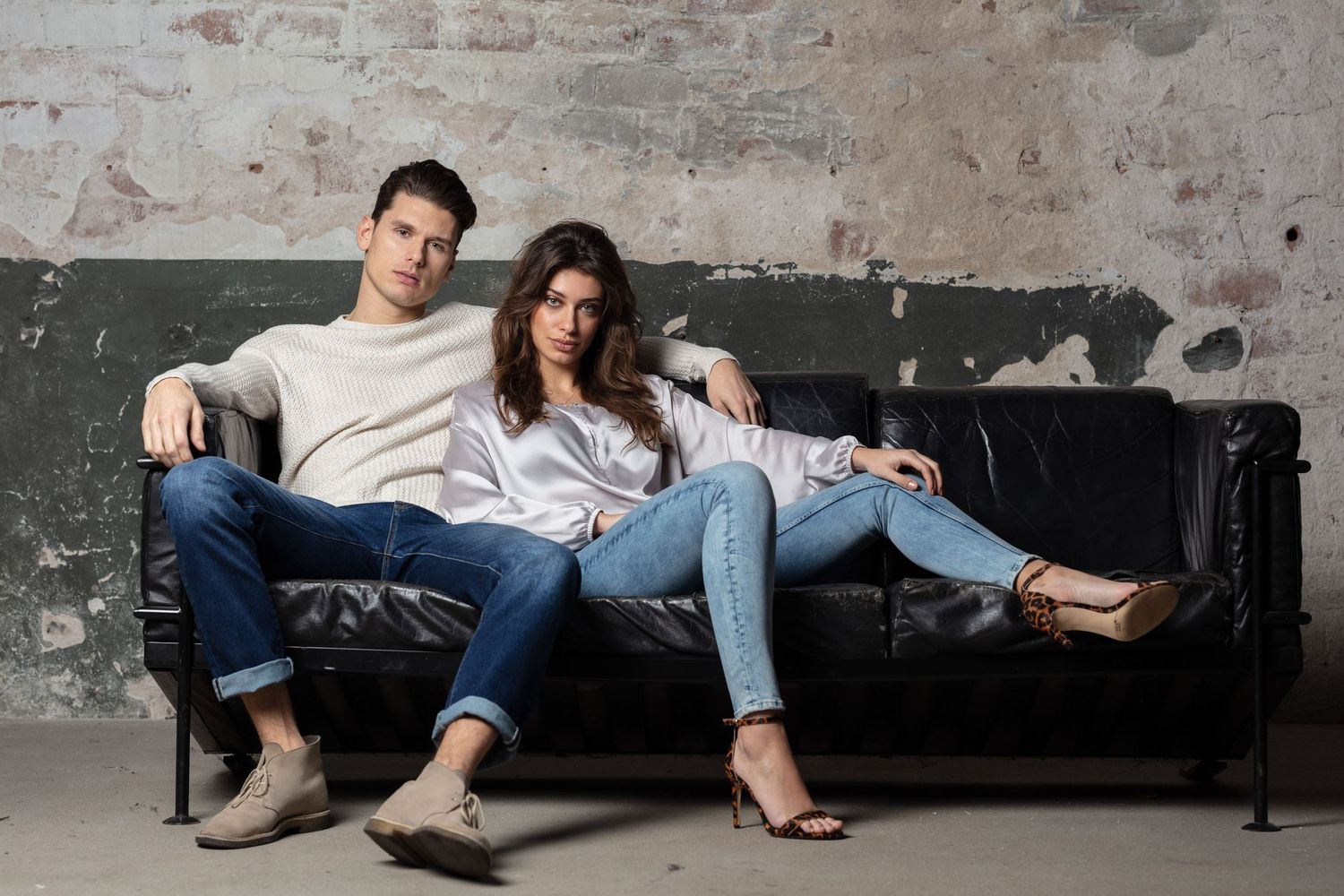 Fashion editorial series showing casual lounging poses on black bench against industrial backdrop.