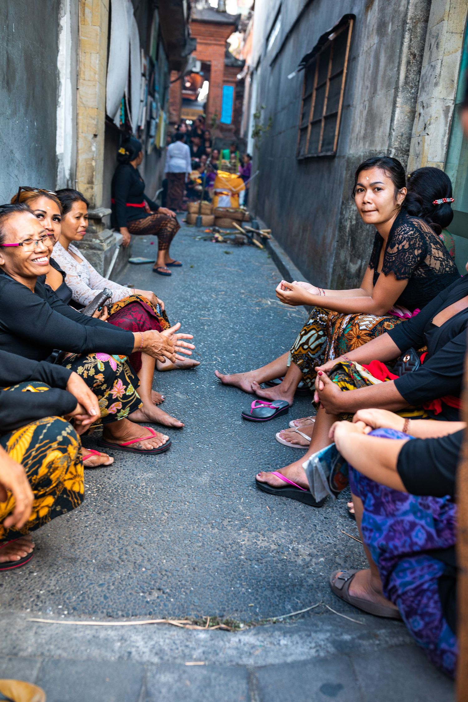 Local residents gathered in narrow alley of traditional Indonesian neighborhood.