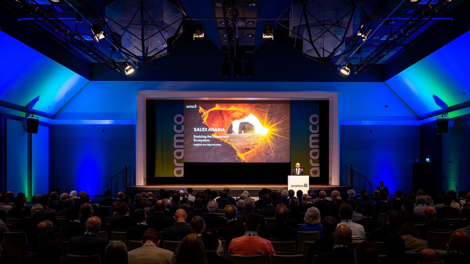 Large conference hall with blue ambient lighting and audience seating.