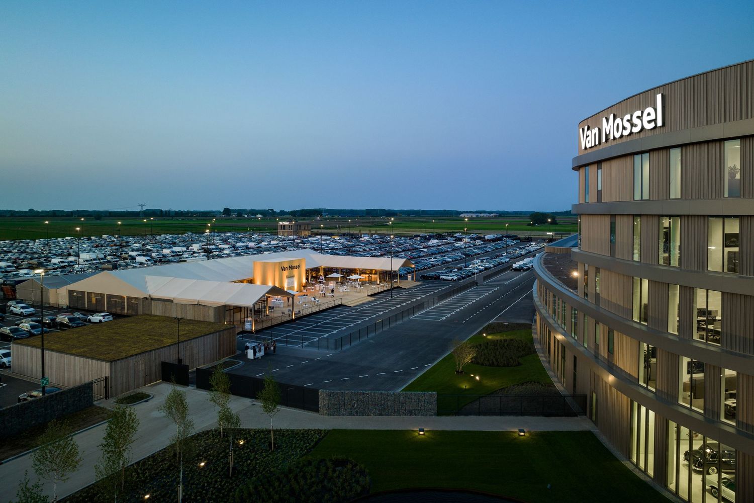 Panoramic view of a beachfront hotel property with multiple buildings and parking areas at sunset.
