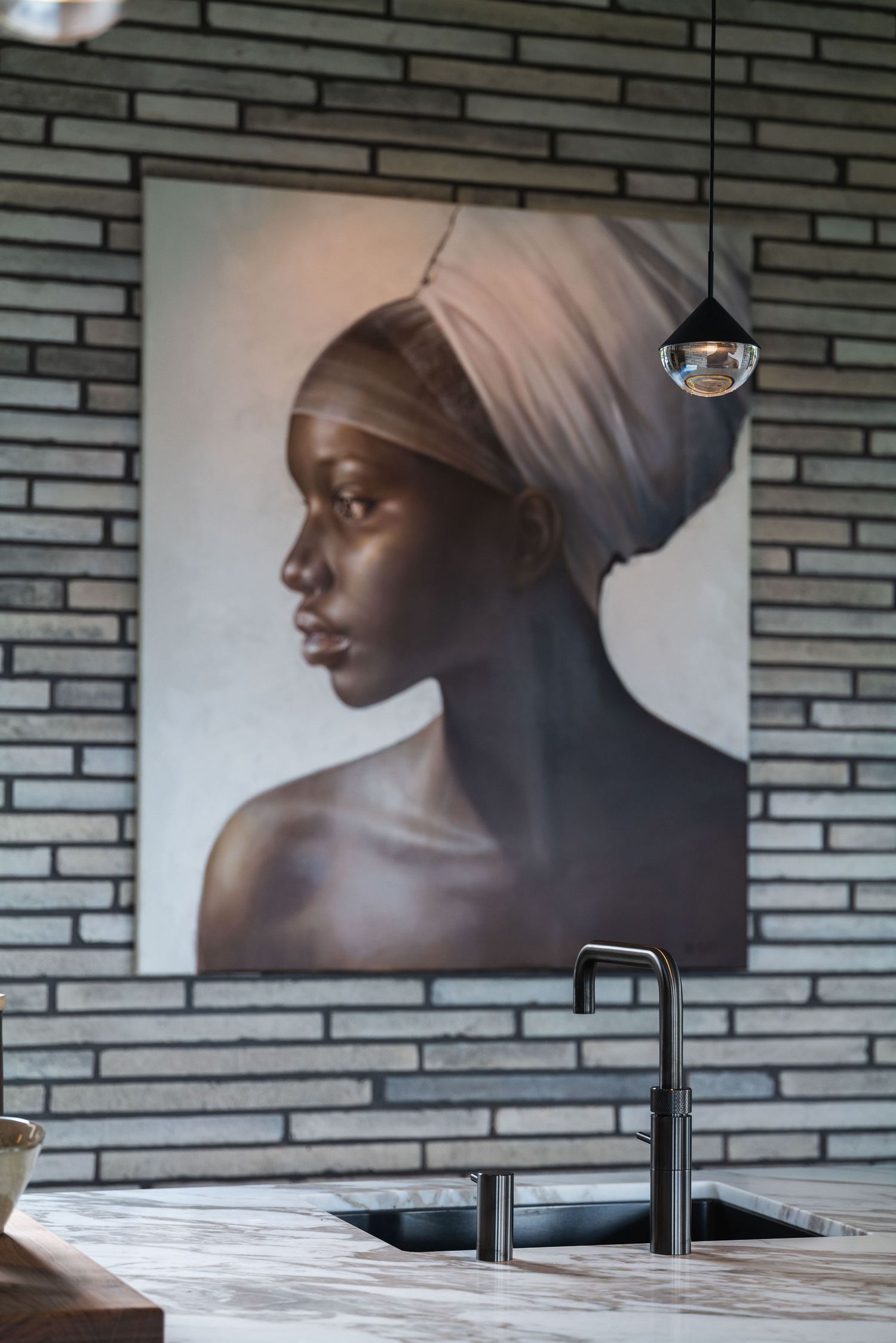 Artistic black and white photography displayed on brick wall above sleek modern kitchen counter.