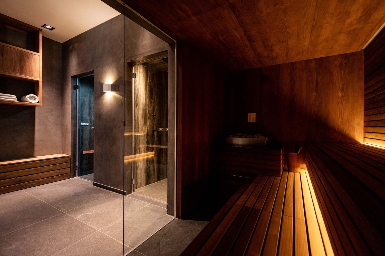 Modern sauna interior with wooden benches and warm lighting creates a relaxing spa atmosphere.