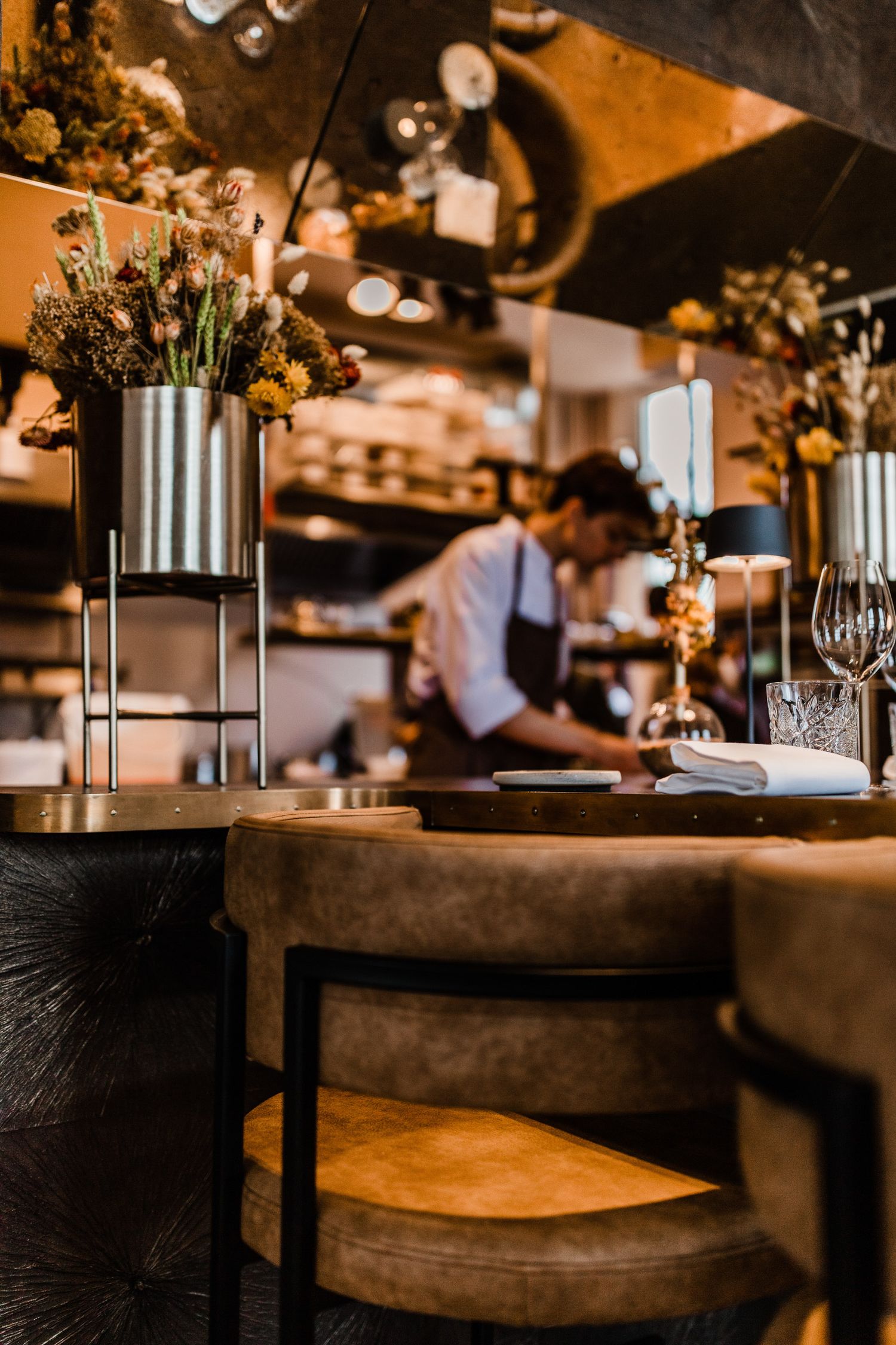 Elegant restaurant interior with wooden tables, chairs and decorative vases illuminated by warm ambient lighting.