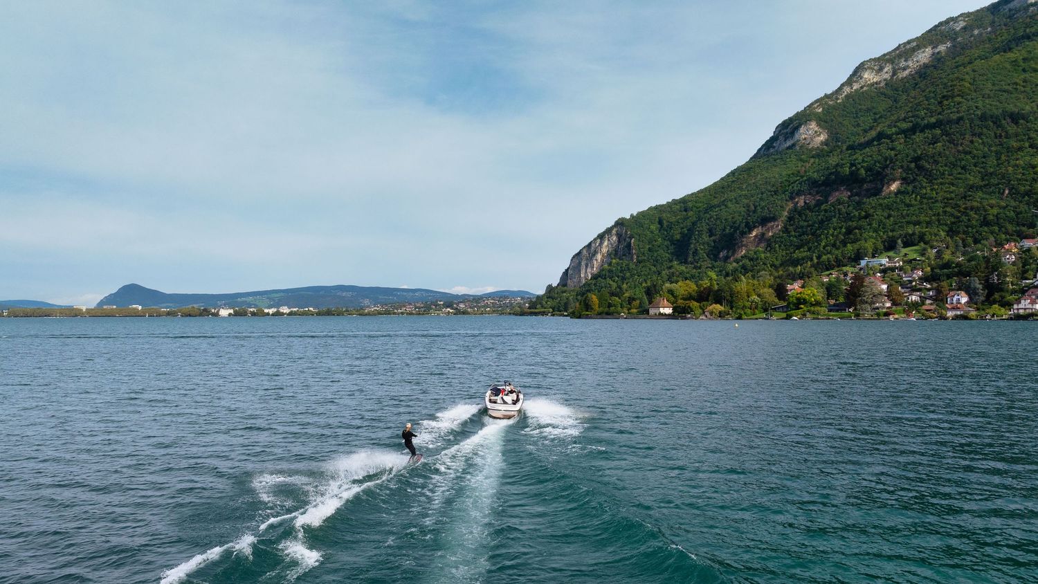 Speedboat creates wake while cruising across a scenic mountain lake on a sunny day.