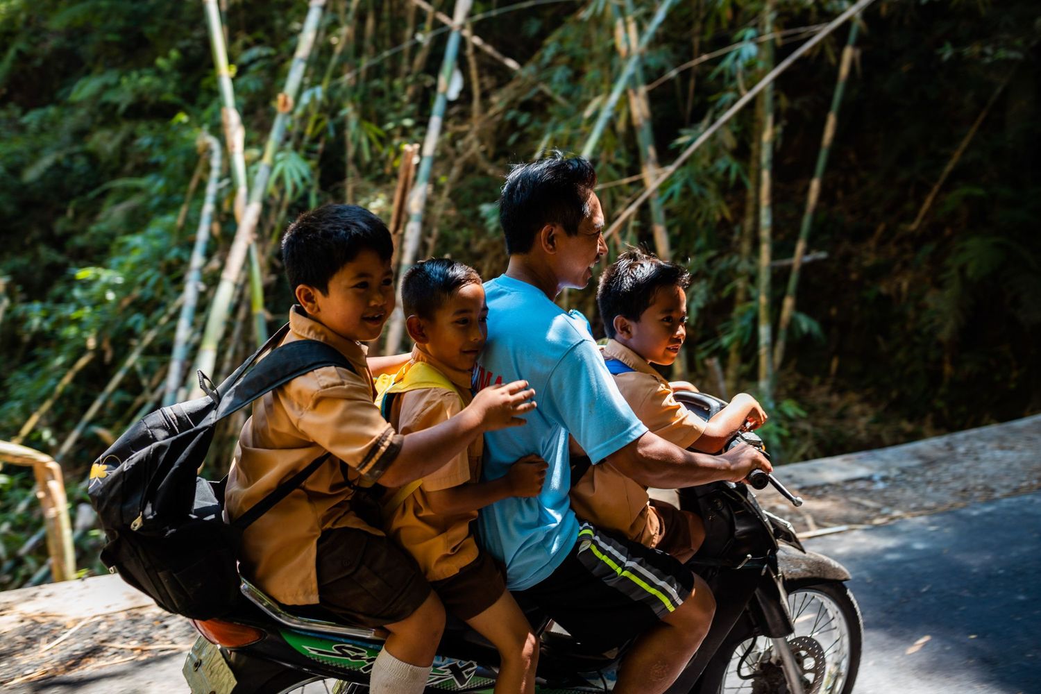 Group riding motorcycles along a winding mountain road surrounded by greenery.