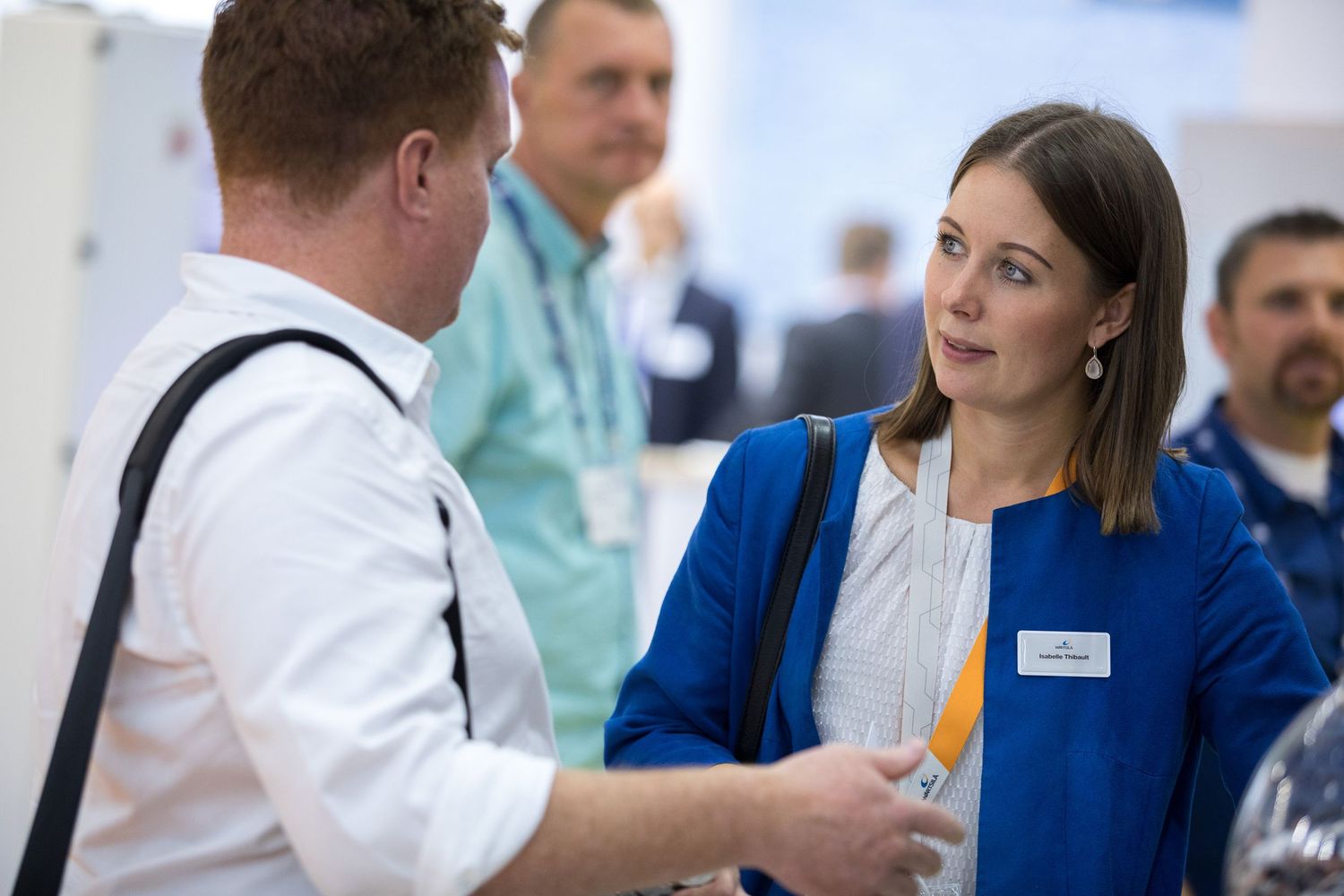 Healthcare professionals in white coats and blue scrubs engage in a discussion in a medical facility setting.