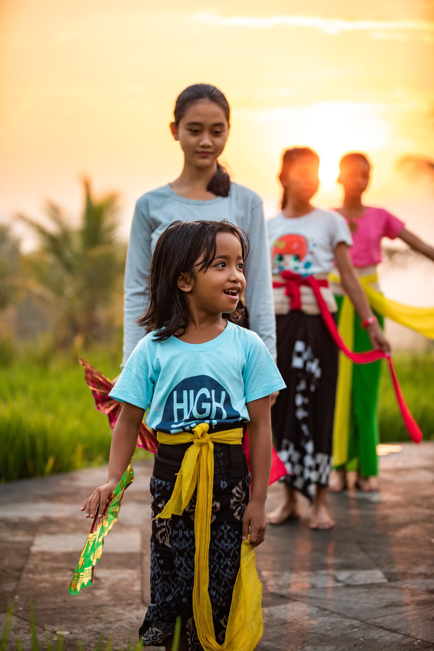Children playing with streamers at sunset wearing bright blue t-shirts.