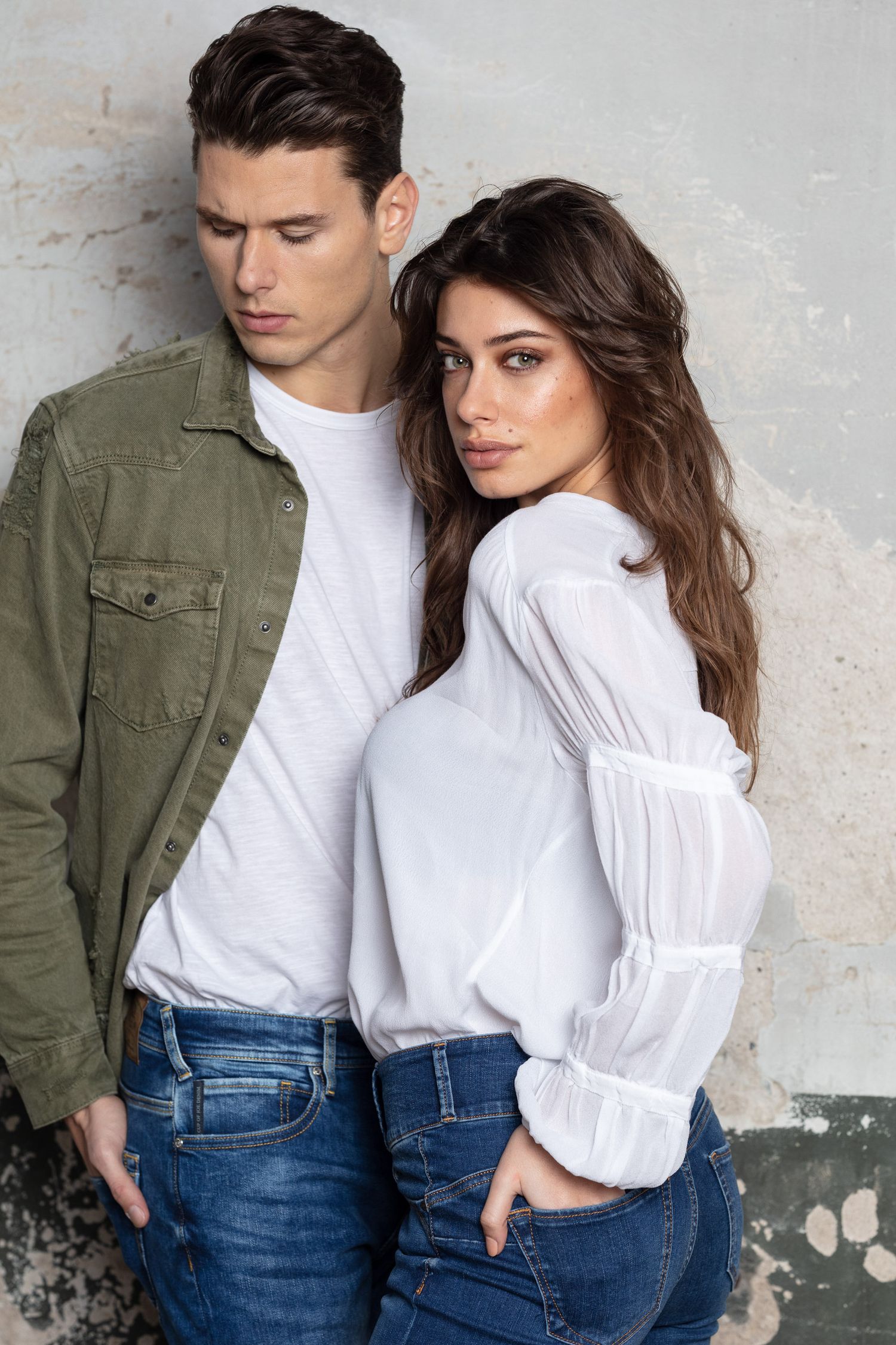 Fashion lifestyle portrait against textured concrete wall background.