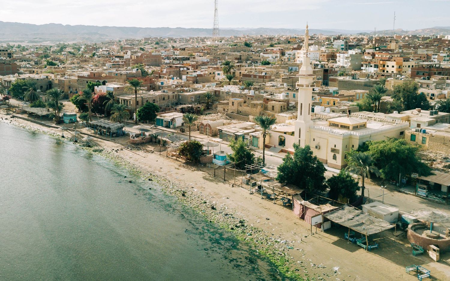 Aerial panoramic view of a coastal city with buildings stretching along the waterfront.