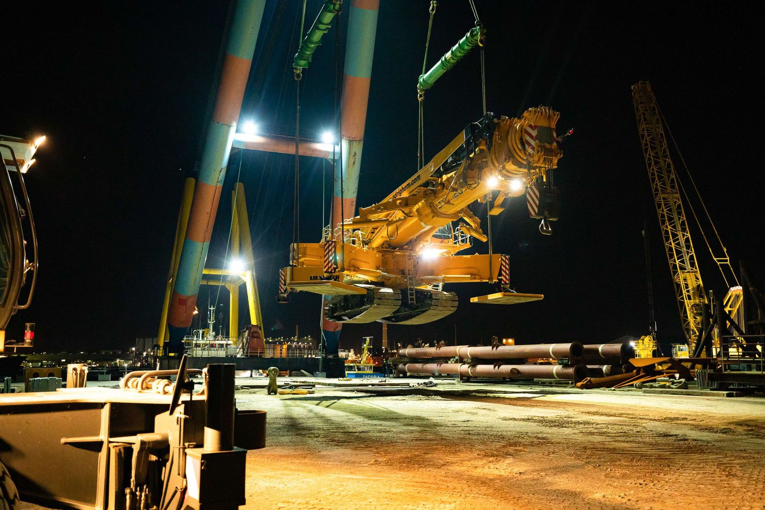 Heavy machinery lifting equipment at night with bright industrial lighting at a construction site.
