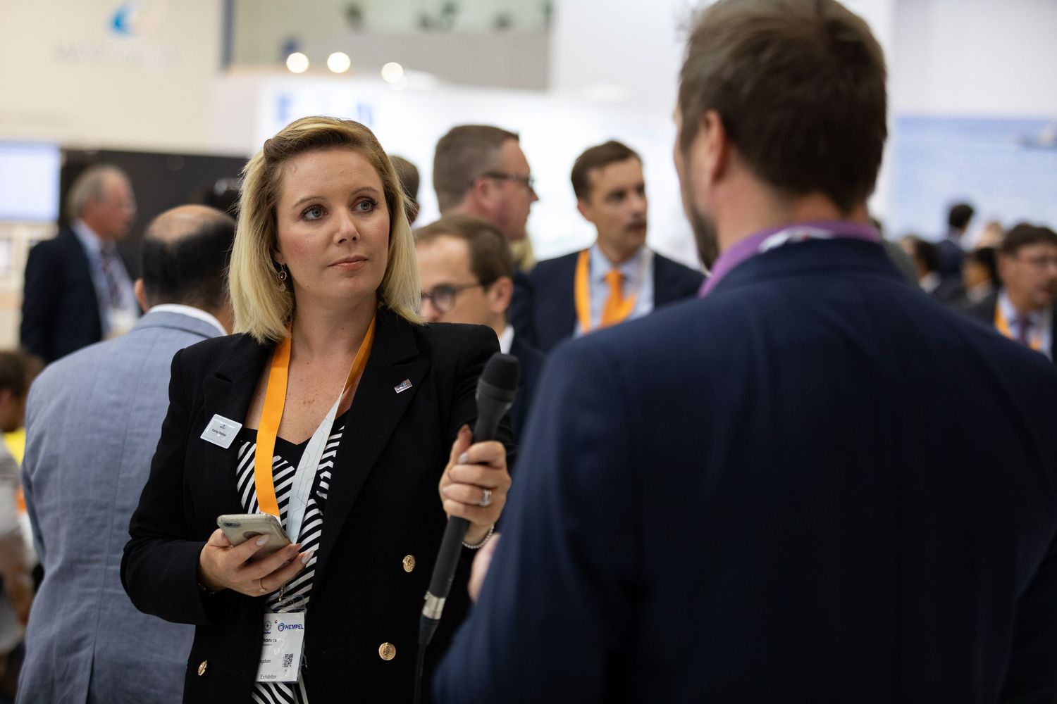 Professional networking event shows attendees in business attire having conversations at a corporate gathering.