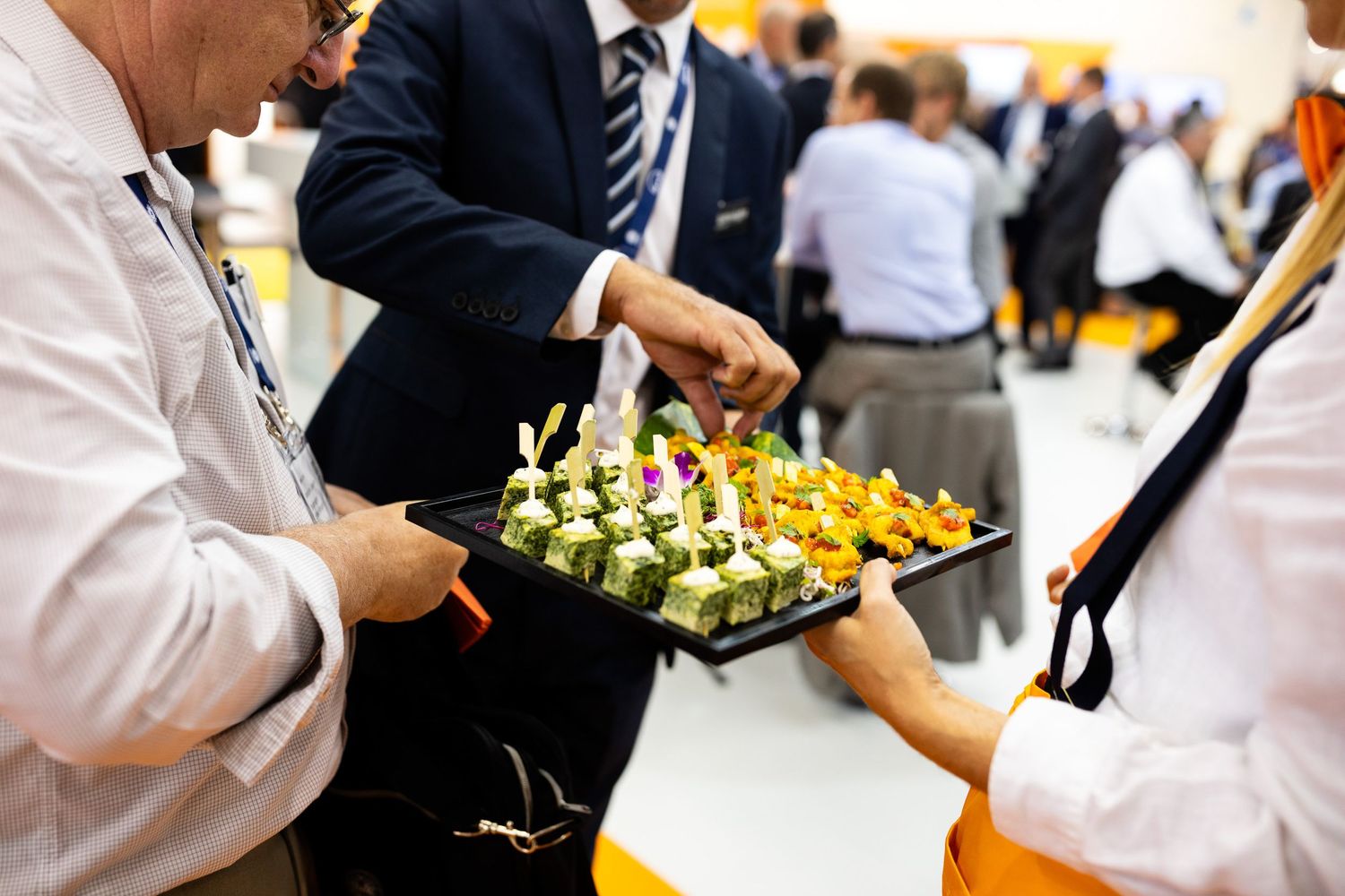 Catering staff serving elegant appetizers on a black tray at an upscale business event.