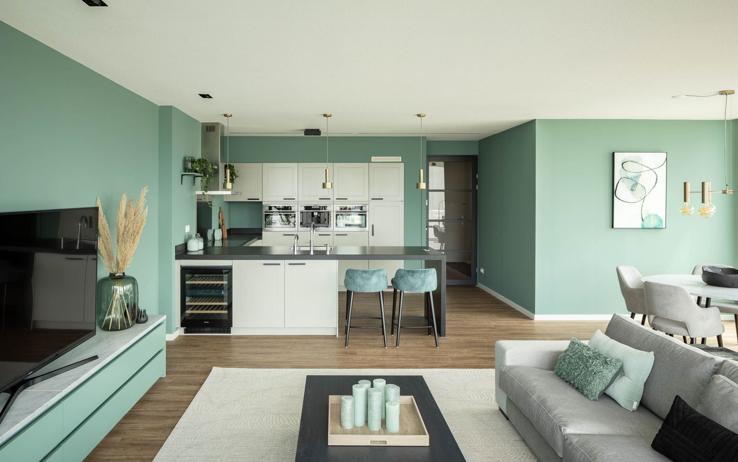 Modern open concept kitchen and living room with mint green walls and white cabinetry features sleek minimalist design.