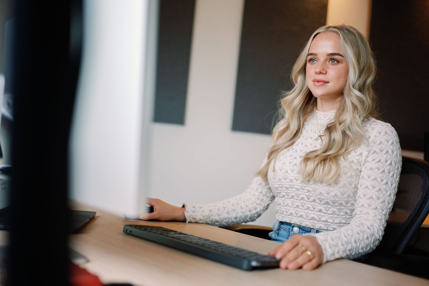 Person sitting at desk with computer in bright modern office space.