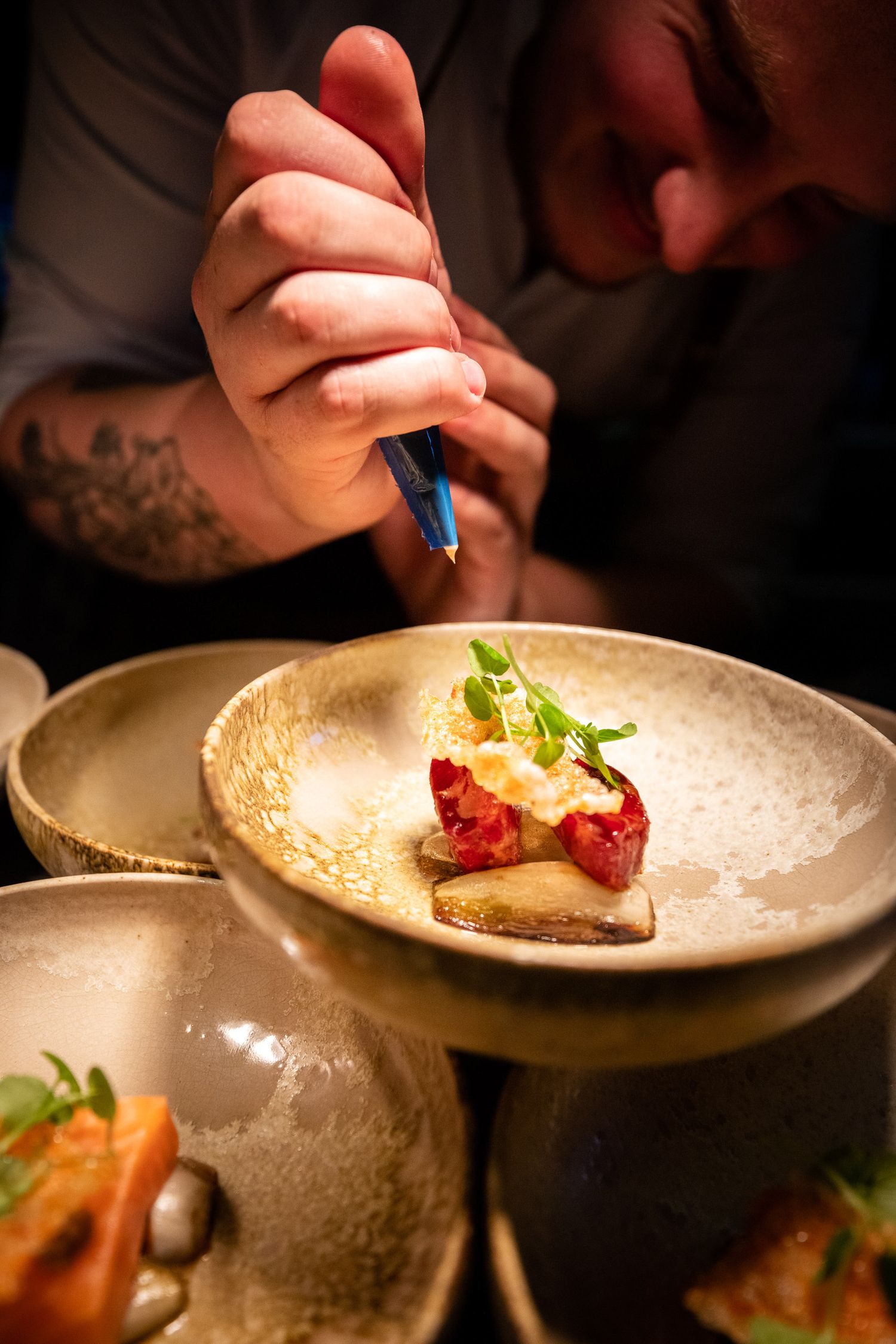 Chef carefully plating and garnishing dishes in a professional kitchen setting.