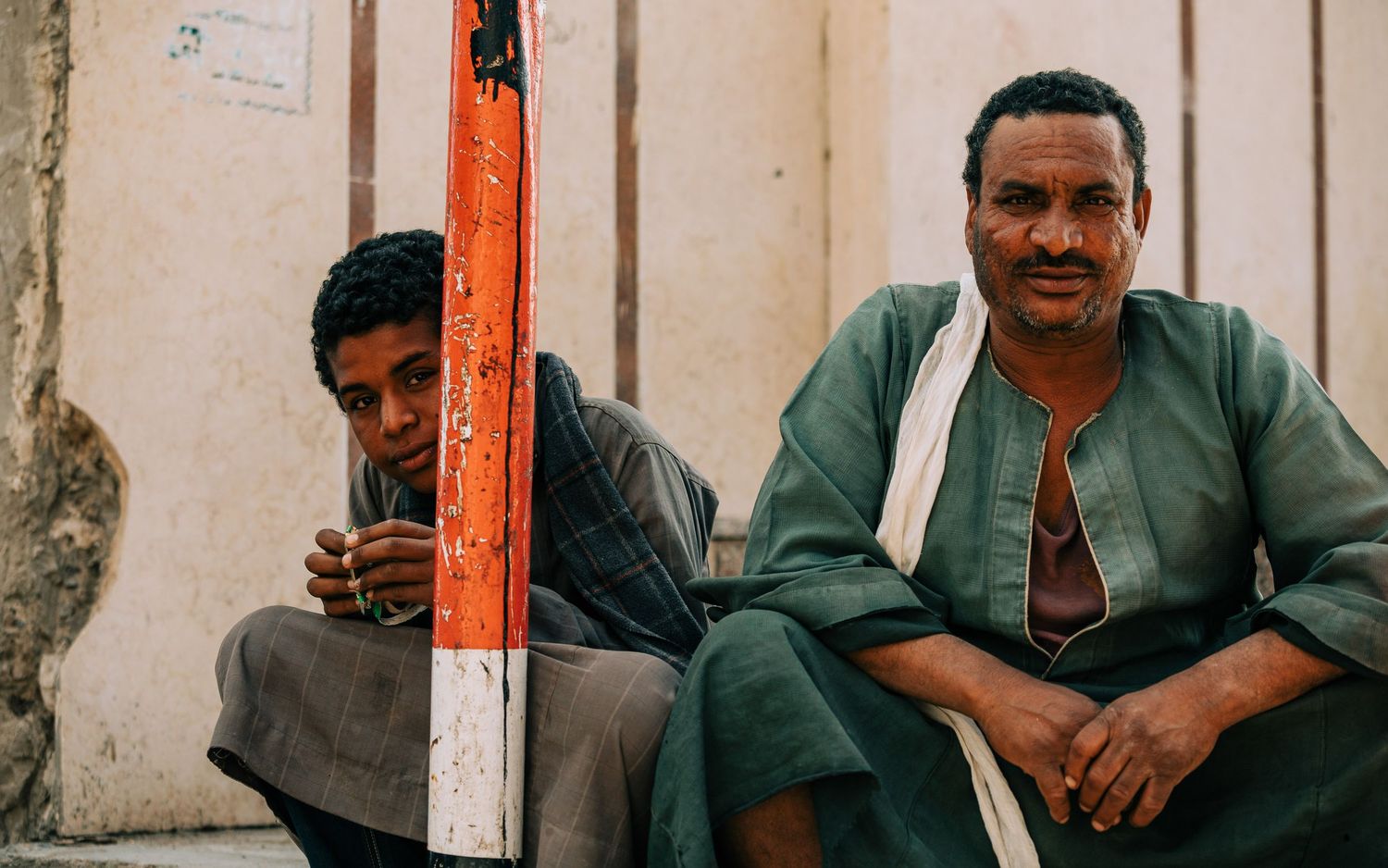 People sitting outside a building with worn walls and rustic character.