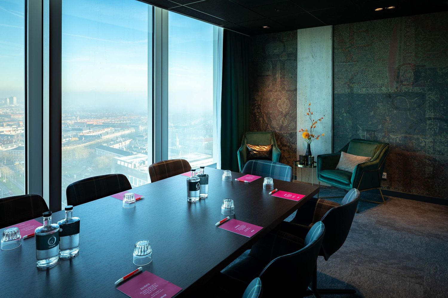 Modern office space with panoramic city views features pink yoga mats laid out on a carpeted floor for a wellness session.