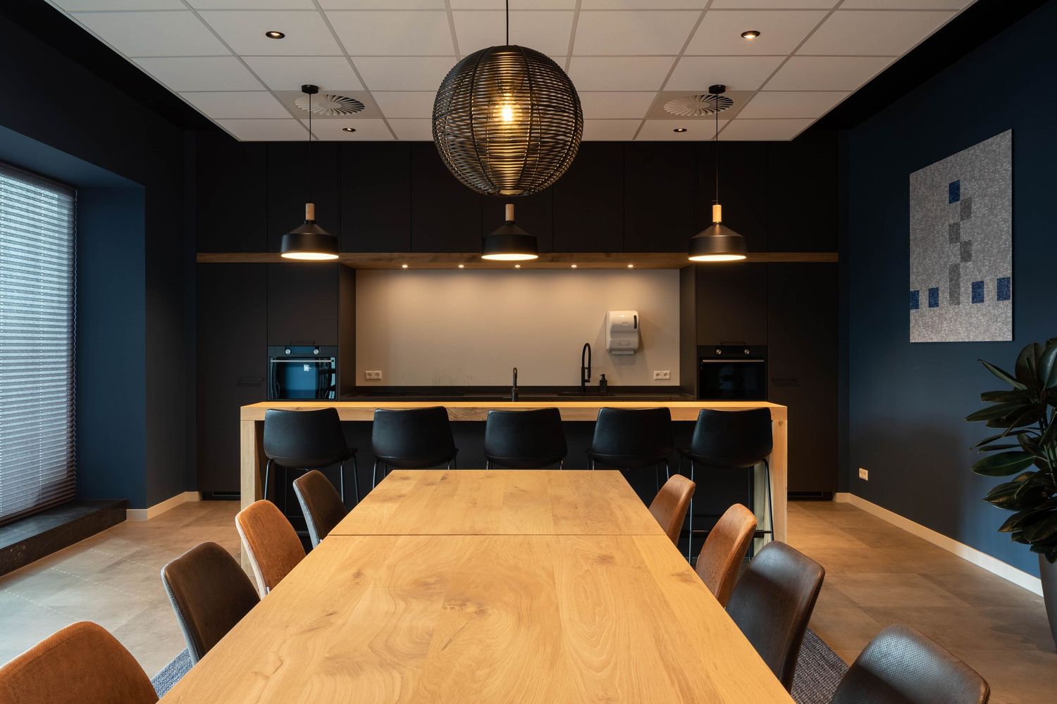 Modern office interior with wooden conference table, pendant lighting, and dark accent walls creates a professional atmosphere.