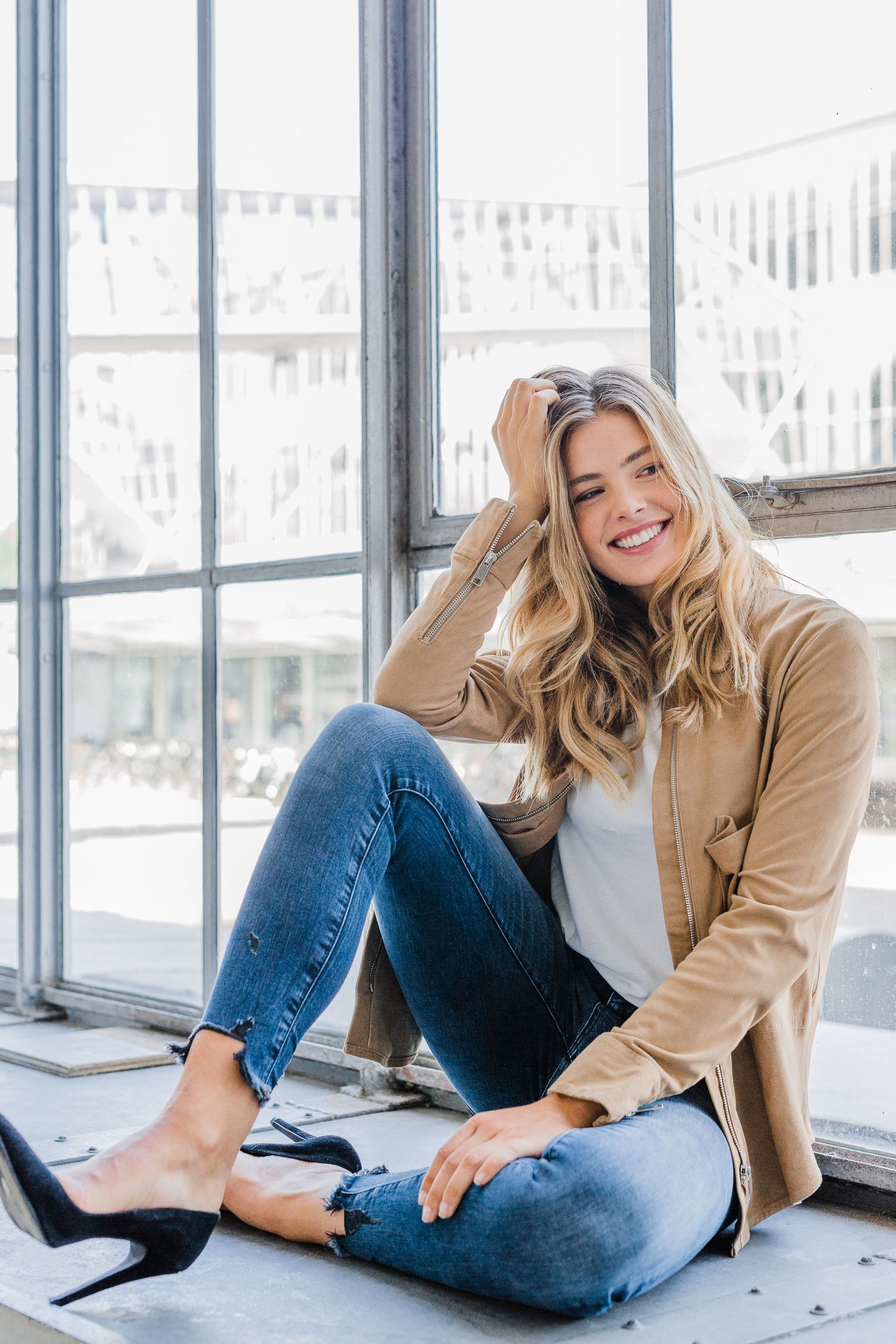 Casual fashion photos showing tan coat and jeans in bright window setting.