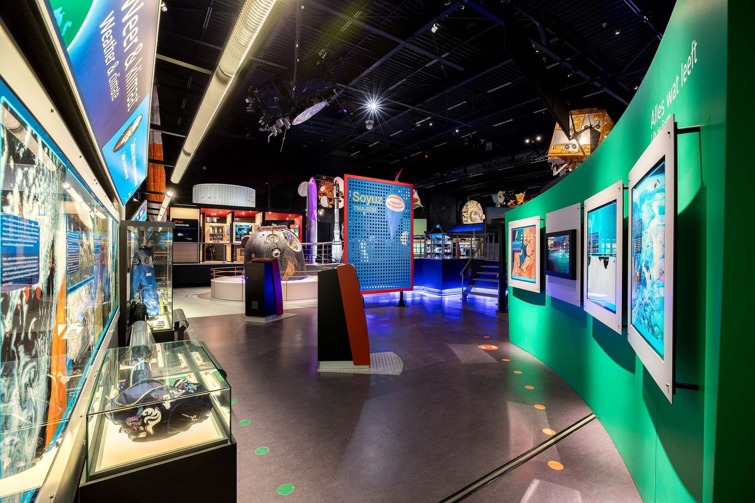 Interactive science museum exhibit hall with illuminated display cases, colorful panels, and engaging educational installations.