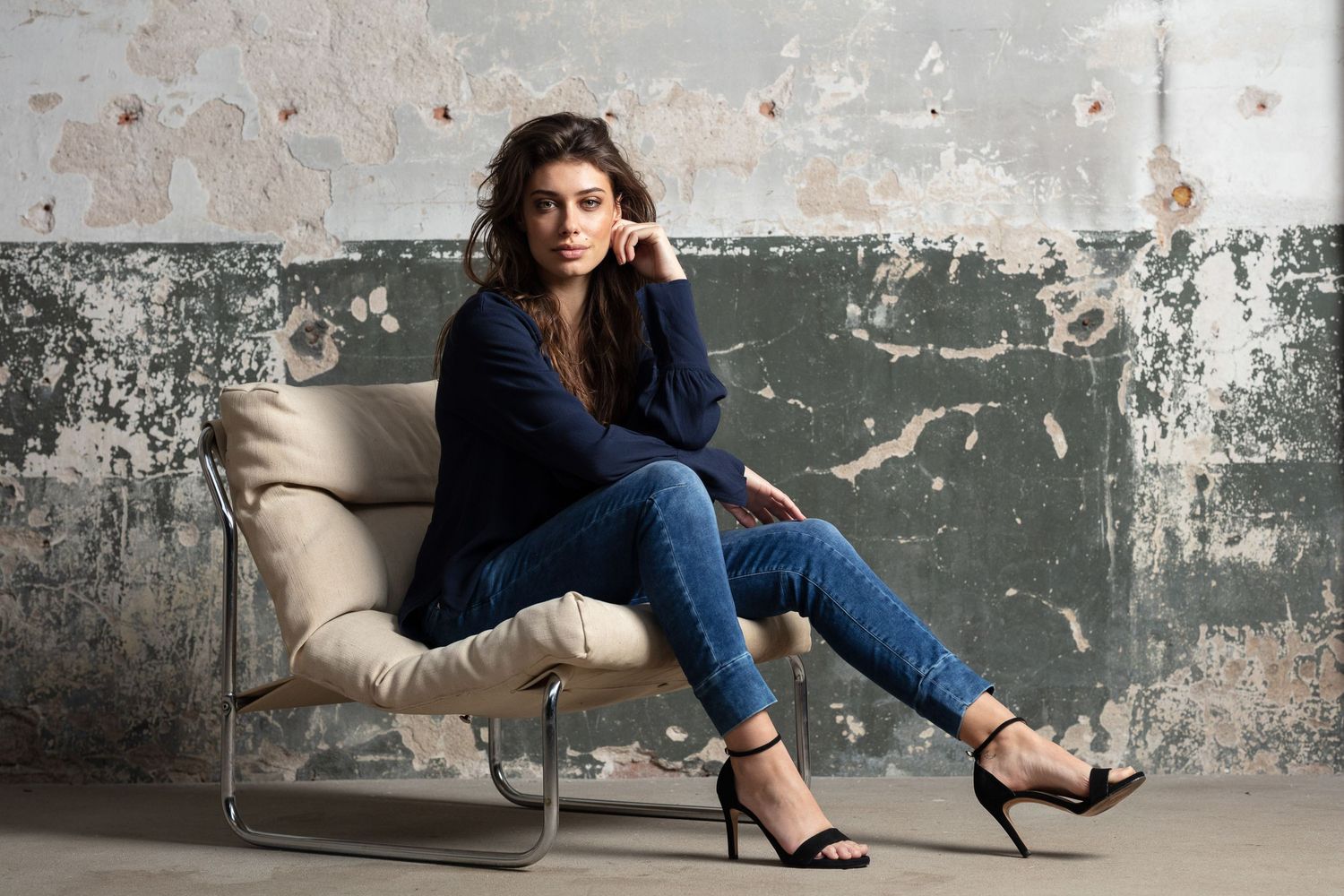 Contemporary fashion scene in industrial setting with weathered wall texture.