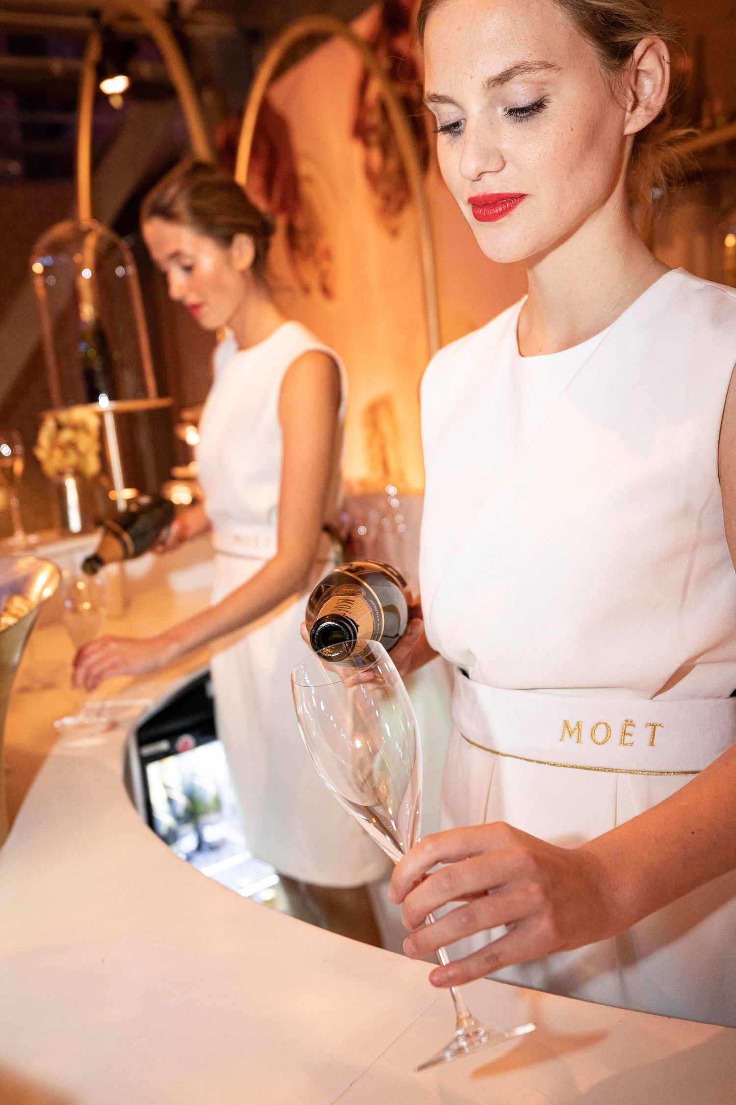 A sequence of photos showing champagne being poured into elegant glasses in a warm, candlelit setting.