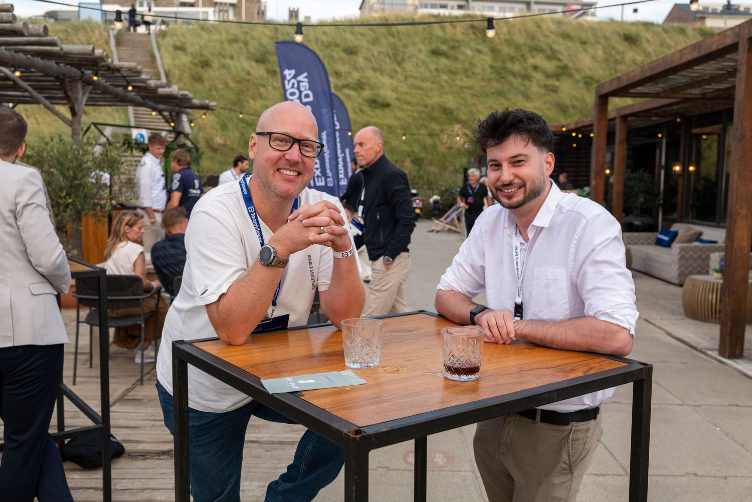 People socializing at outdoor tables during a corporate event.