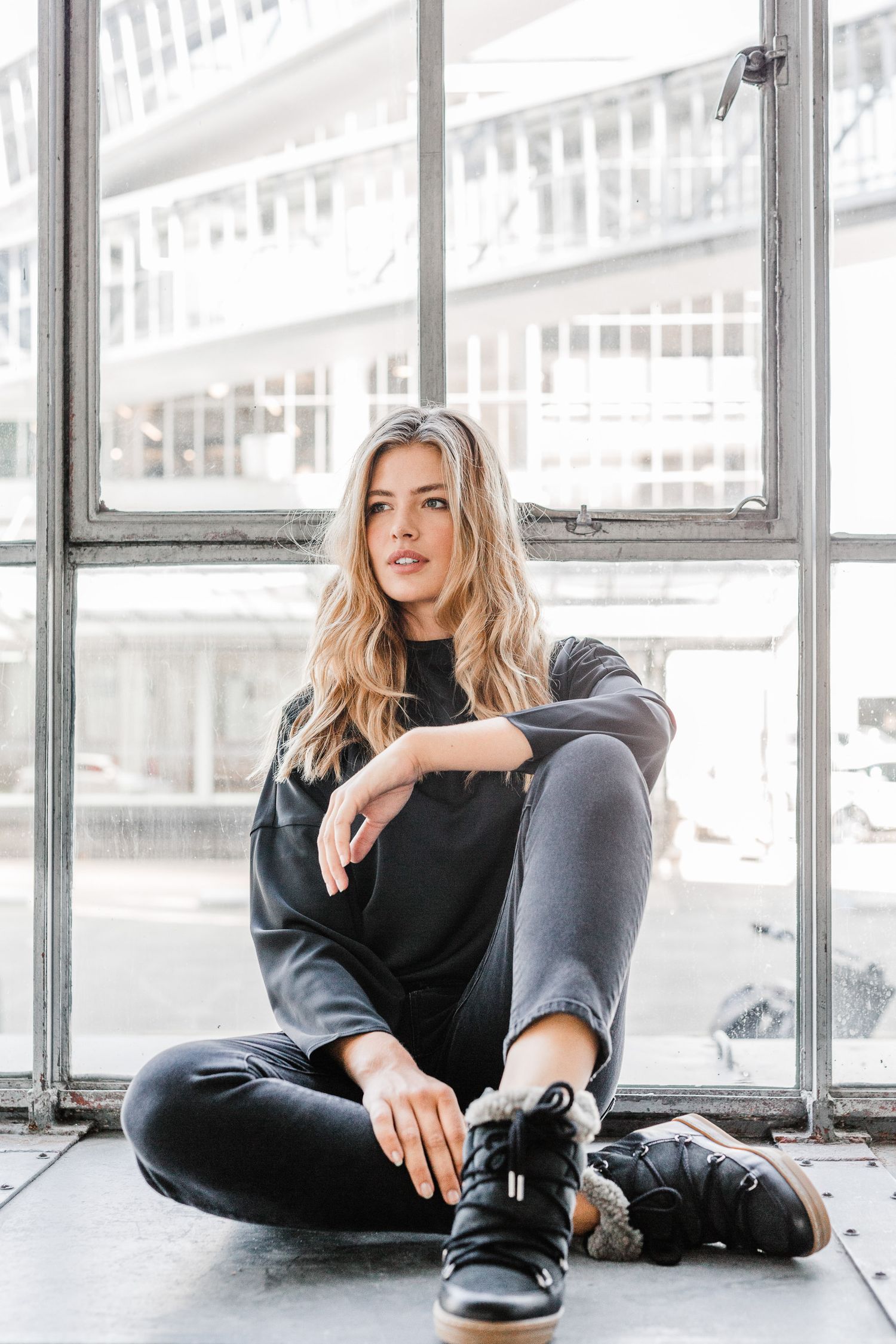 Casual fashion portraits featuring black sweater and jeans in bright industrial setting.