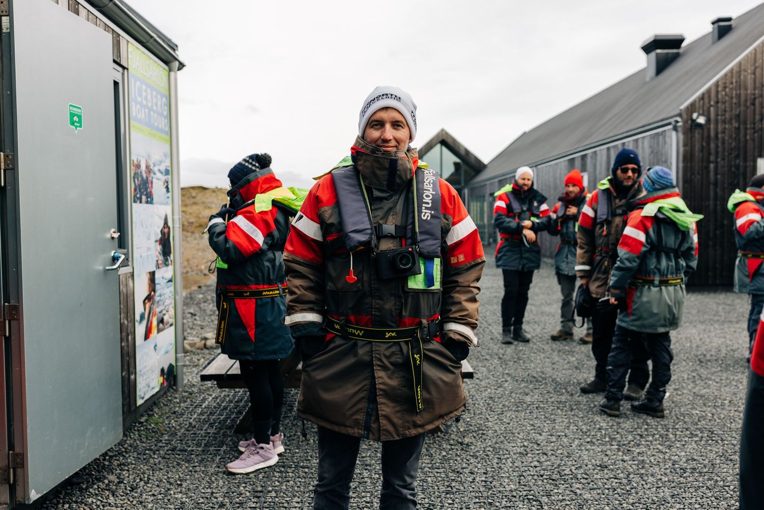 A group of rescue workers in high-visibility winter gear gather outside storage units in cold weather conditions.