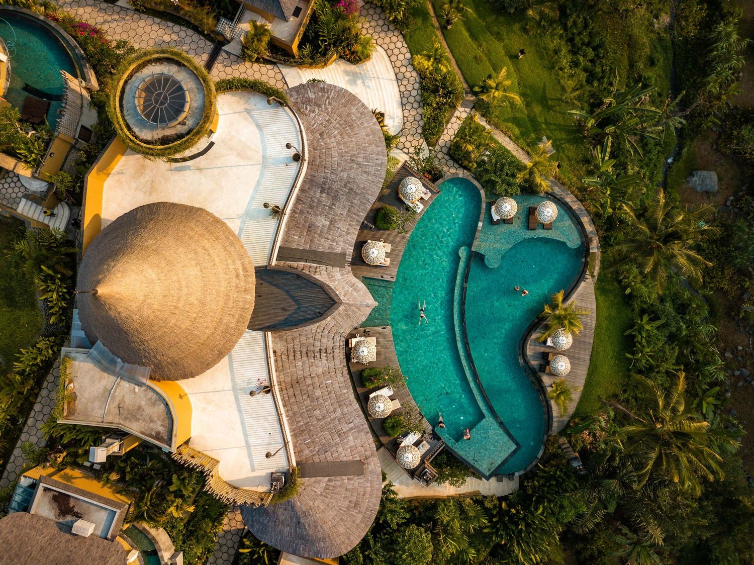 Aerial view of luxury eco-resort villas with swimming pools surrounded by lush tropical vegetation.