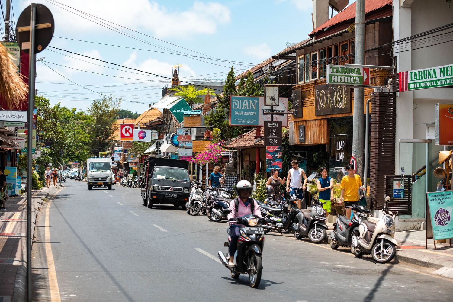 Quiet suburban street with motorcycles and small shops in a Southeast Asian neighborhood.