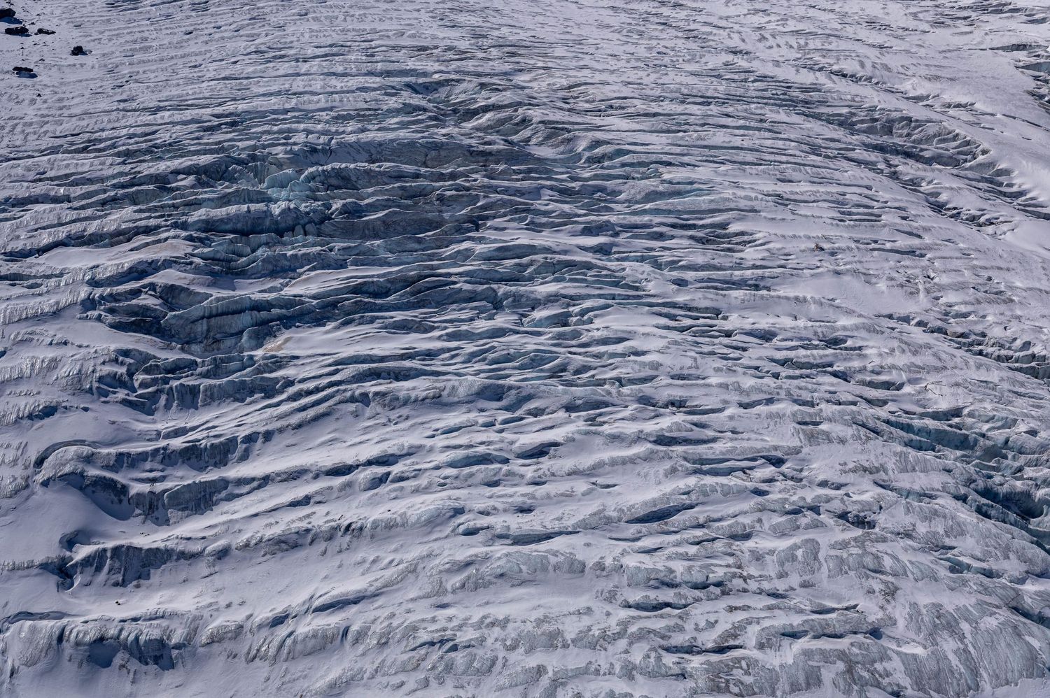 Close-up texture of snow and ice formations on a glacier surface in the Swiss Alps.