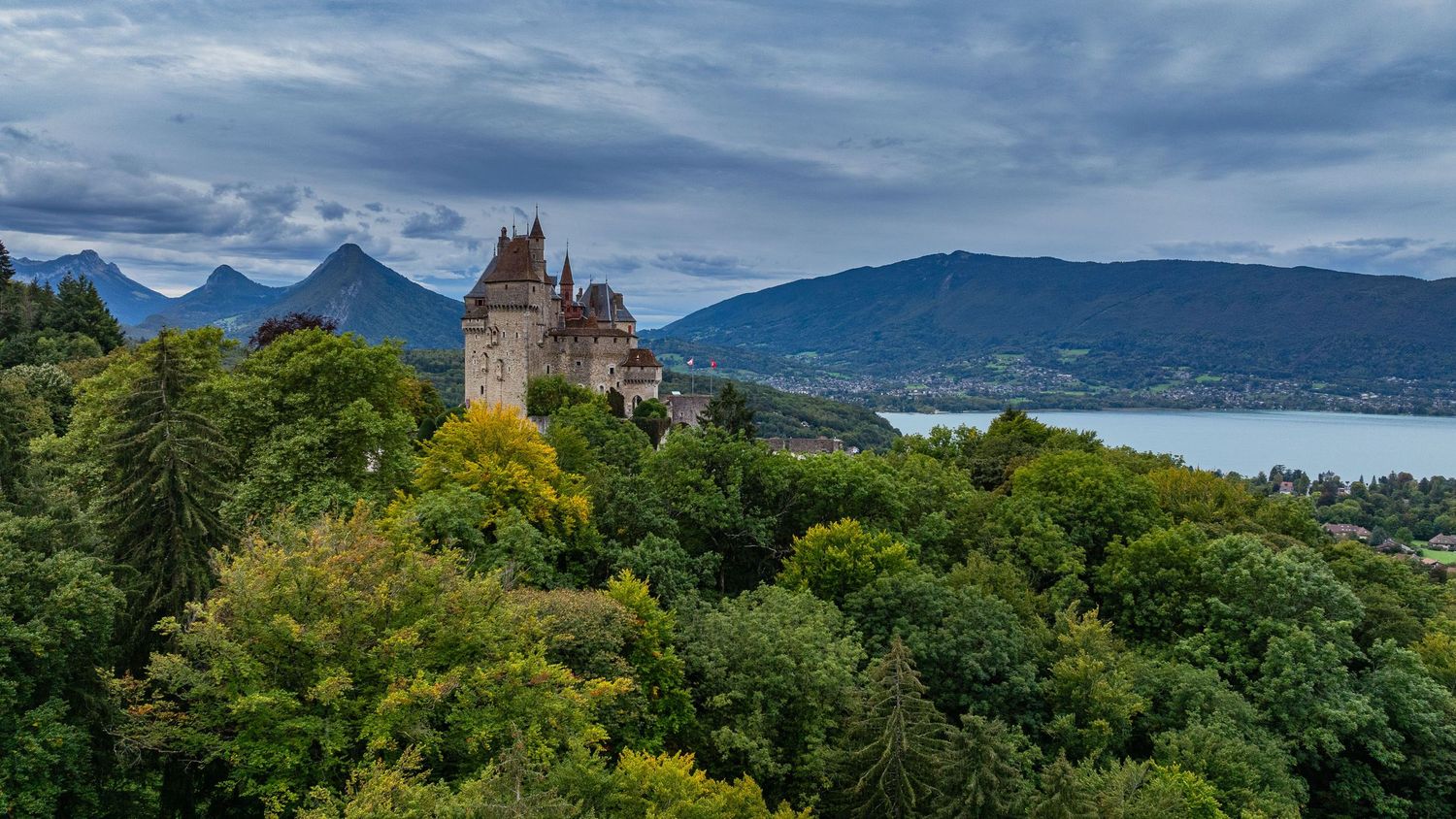 Mountain landscape with lake views and historic architecture nestled among autumn trees.