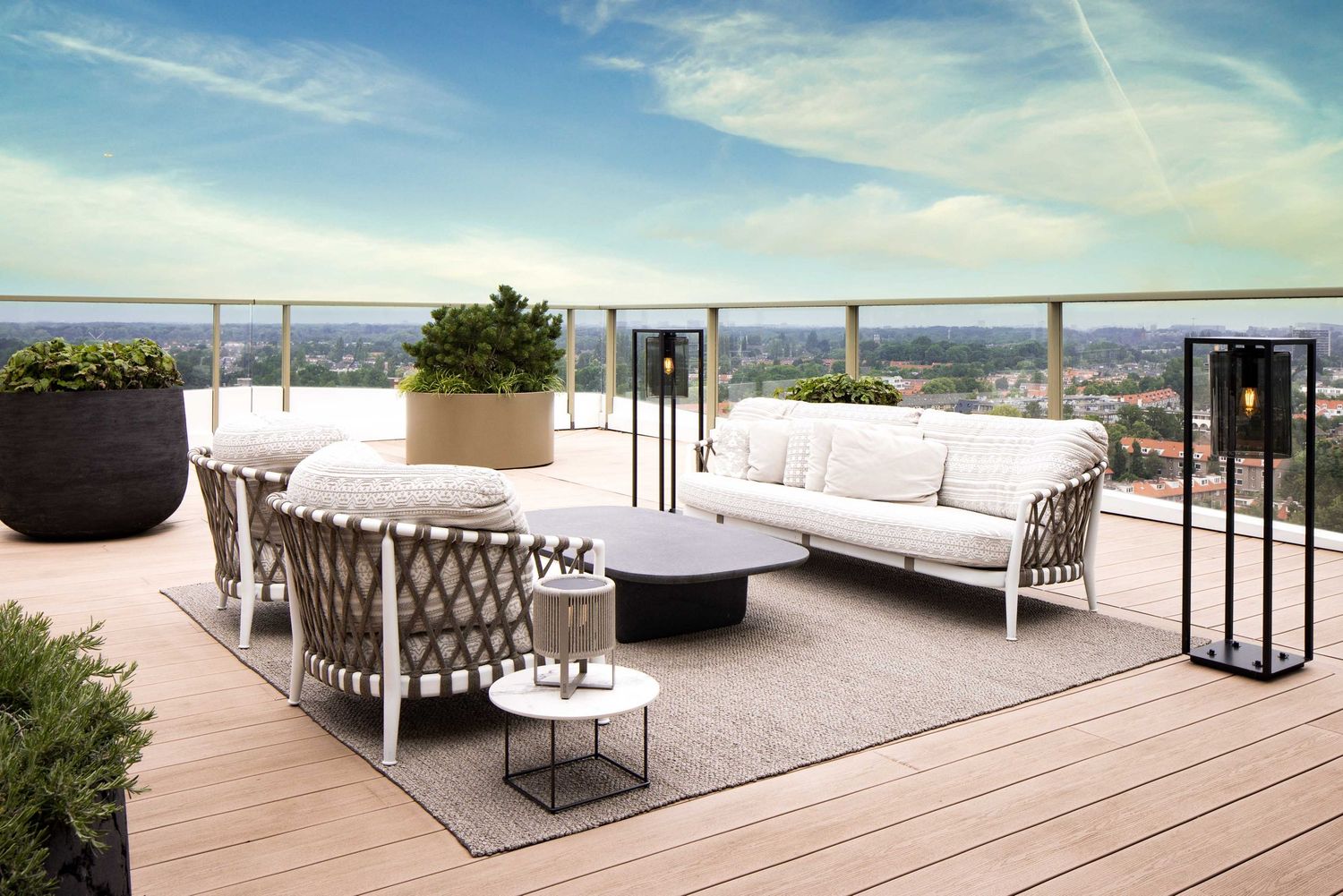 Modern outdoor terrace with sleek metal furniture and panoramic ocean views under a bright blue sky.